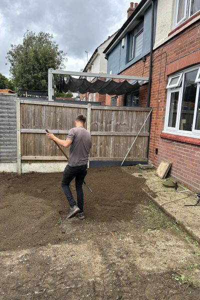 A member of the Green Growth team appplying top soil after a garden clearance.